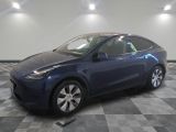 une Tesla Model Y bleue garée dans une pièce au sol à carreaux