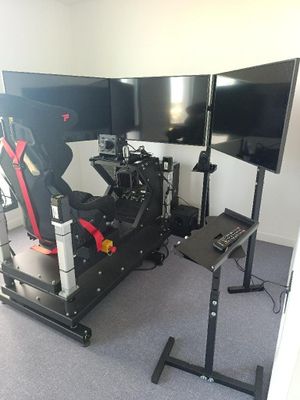 a computer desk with two monitors and a racing simulator