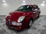 La voiture Alfa rouge est garée dans une grande pièce au sol carrelé en damier.
