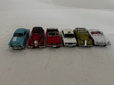 several toy cars are lined up in a row on a white surface