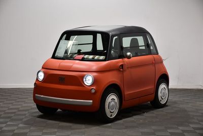 une image représentant une petite voiture orange sur un sol à damier