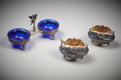 trois bols en verre argenté et bleu, munis d'anses, posés sur un plan de travail blanc