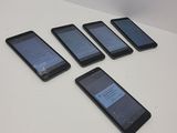 five cell phones are lined up on a table with a white background