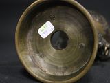 a bronze vase that has a tag on it