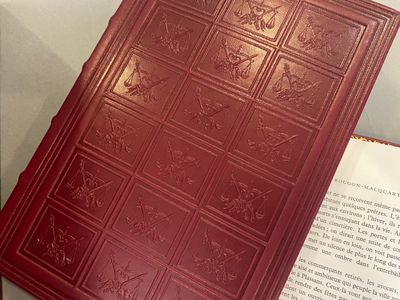 a red book sitting on top of a table next to an open book