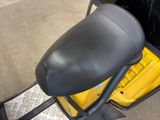 a black seat on a yellow scooter parked in a garage