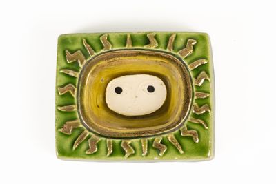 a small ceramic object with a smiley face in the center