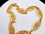 a close up of a gold plated bracelet on a white surface