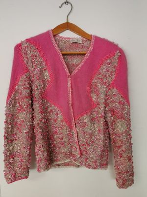 un cardigan rose suspendu à un cintre