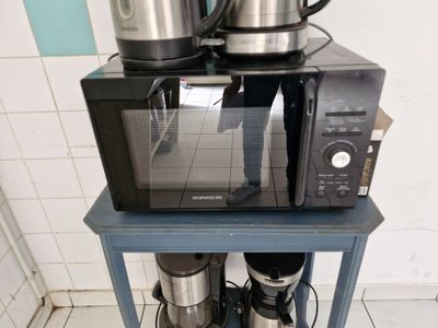 un micro-ondes et une cafetière posés sur une petite table bleue