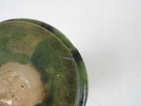 a close up of a green and black bowl on a white surface