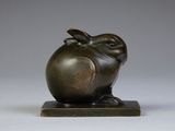 a bronze statue of a frog sitting on top of a wooden base