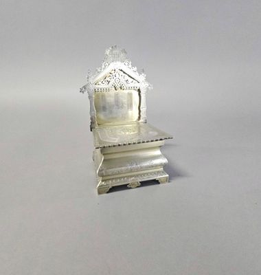une petite horloge en argent posée au sommet d'une pile de livres