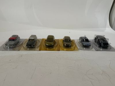 several toy cars are lined up in plastic bags on a white surface