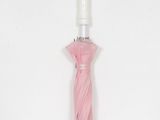 a pink umbrella with a white handle on a white surface