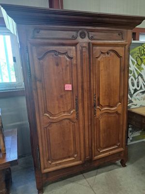 une armoire en bois dans une pièce où se trouvent une table et des chaises