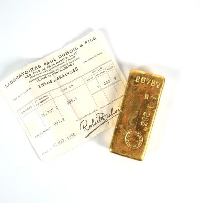 un lingot d'or et un reçu posés sur une surface blanche
