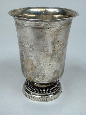 an old silver cup with a metal base on a white surface