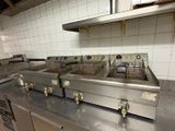 several deep fryers are lined up on a counter in a commercial kitchen
