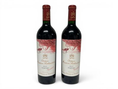 two bottles of red wine sitting next to each other on a white surface