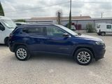 a blue jeep compass parked in a parking lot next to a white van