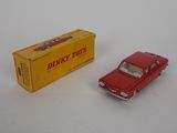 a red toy car sitting next to a yellow box