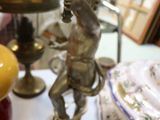 une horloge posée sur une table, surmontée d'une statue