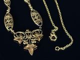 gold necklace with a star and a flower design on a black background