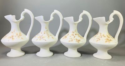 quatre vases blancs ornés de motifs dorés, posés sur une table