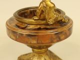 brass figurine of a boy sitting on a pedestal with a bowl