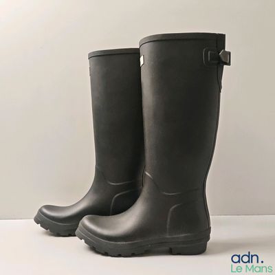 une paire de bottes de pluie noires posées sur une surface blanche