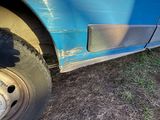 a blue truck that has a tire on the side of it