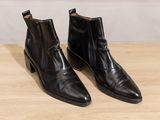 a pair of black boots sitting on top of a wooden table