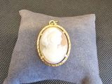 une photo d'une broche-camaïeu dorée et blanche posée sur un coussin