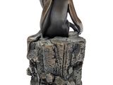 statue of a woman sitting on a tree stump with her back to the camera