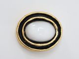 black and white button with gold trim on a white surface
