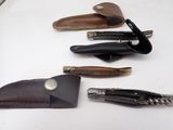 five different types of leather sheaths on a white table