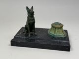statue of a dog sitting on a base next to a lamp