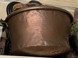 a large copper pot sitting on a shelf next to a potted plant