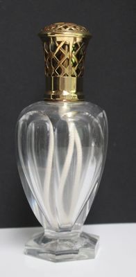 un vase en verre avec un couvercle doré posé sur une table blanche
