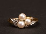 gros plan d'une bague en or avec des perles et des diamants