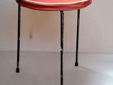 a small table with a red top sitting on a white floor