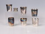 several silver cups and cups are lined up on a white surface