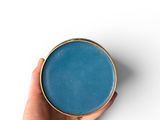someone is holding a blue bowl in their hand on a white surface