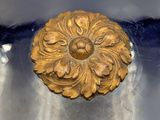 a close up of a gold flower on a blue vase