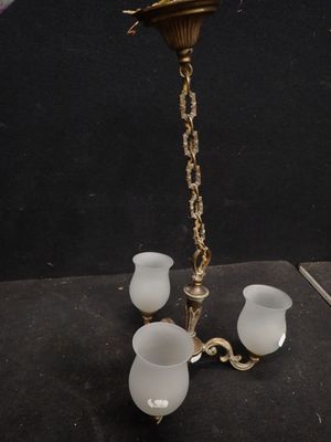 un lustre ancien en laiton avec des abat-jours en verre dépoli
