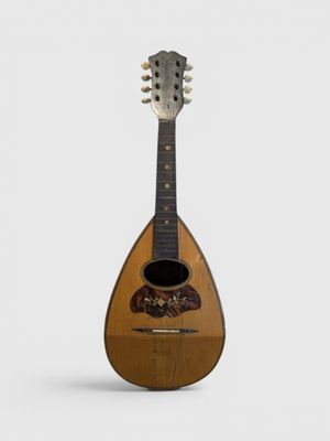 une vieille guitare au corps en bois posée sur une surface blanche
