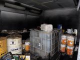 many barrels and containers of paint in the back of a truck