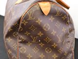 louis vuittou bag on a black surface with a white wall in the background
