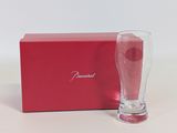 an empty glass next to a red box on a white surface